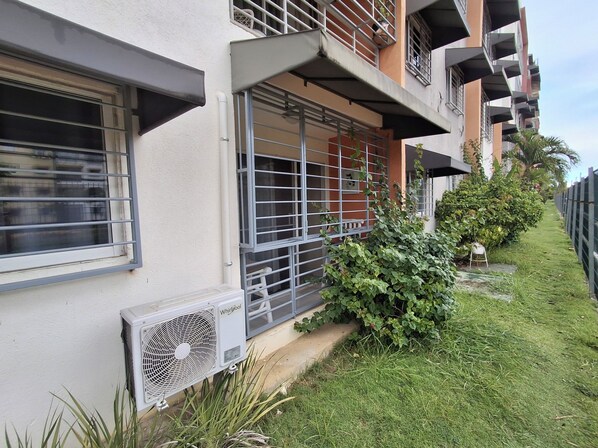 Residential building with modern architecture, featuring flat facade, balconies, and a well-manicured lawn.
