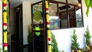 A hotel entrance with a glass door, a logo on the door, and a wooden ceiling. - Kings Residency (Tiruvannamalai)