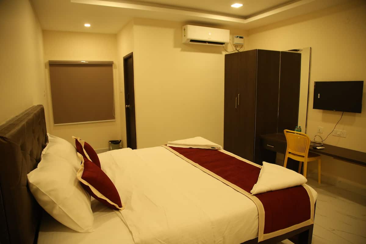 A hotel room with a bed, a desk, a chair, a wardrobe, and a TV.