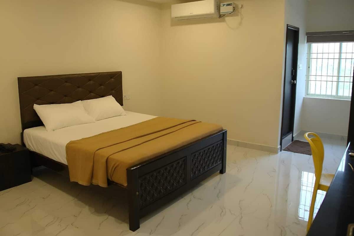 A bedroom with a bed, a bedside table, an air conditioning unit, and a window with bars.