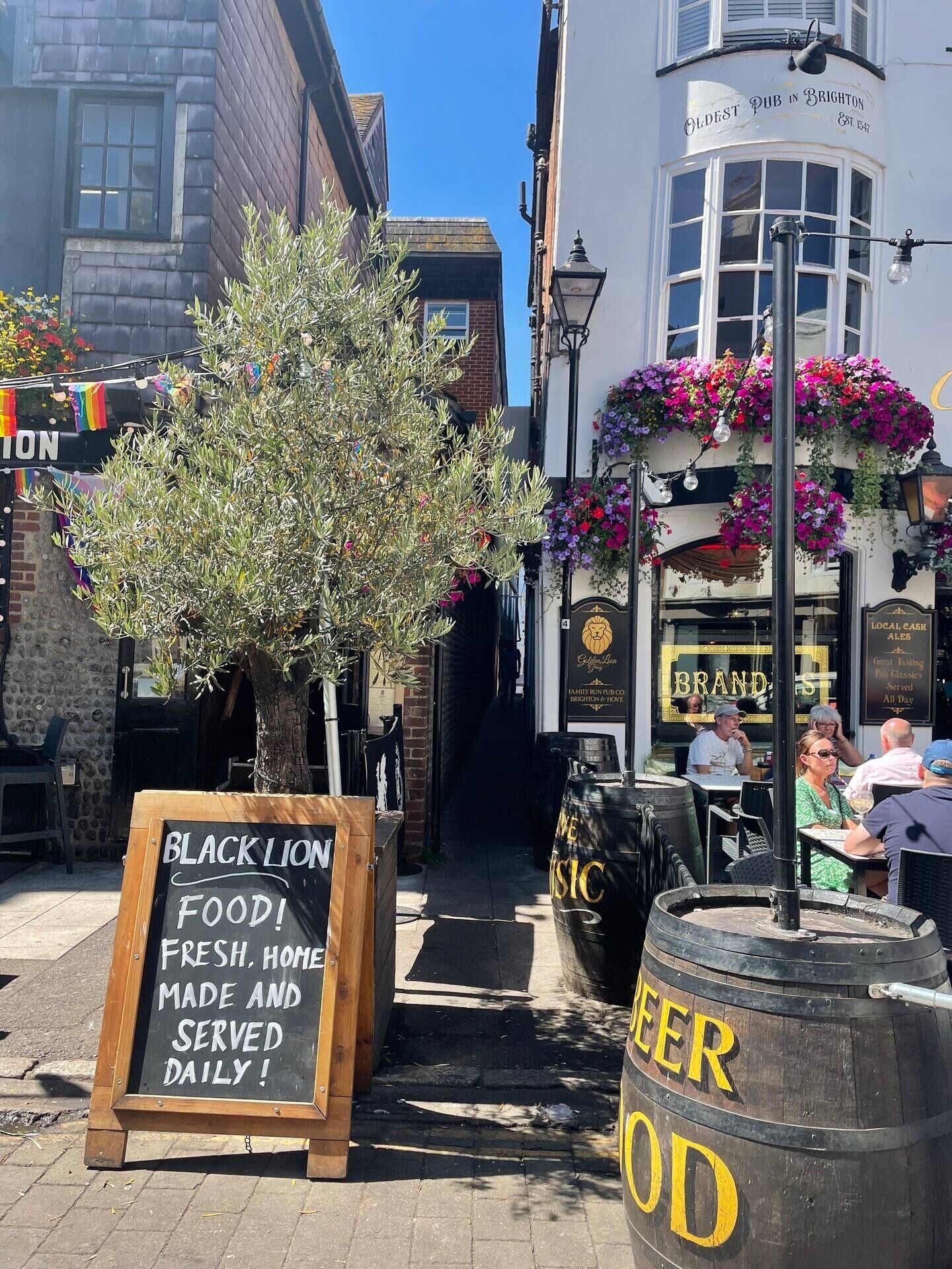 A pub with outdoor seating, a signboard for Black Lion Food, and a beer barrel.