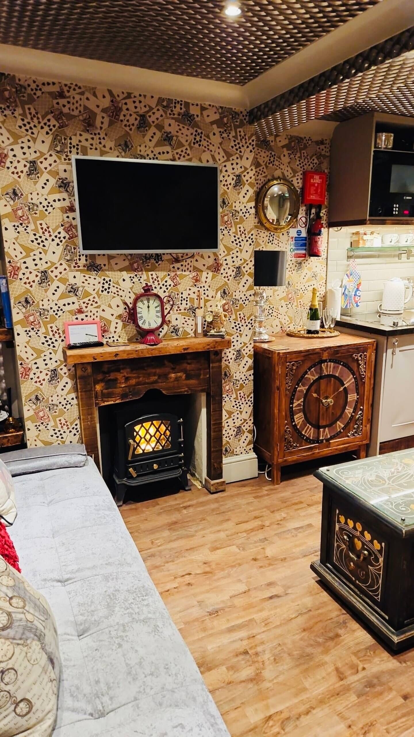 A cozy living room with a fireplace, a clock, and a television mounted on the wall.