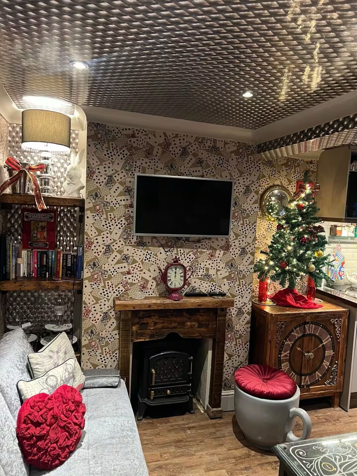 Ein gemütliches Wohnzimmer mit Kamin, Bücherregal, Flachbildfernseher und Weihnachtsbaum.