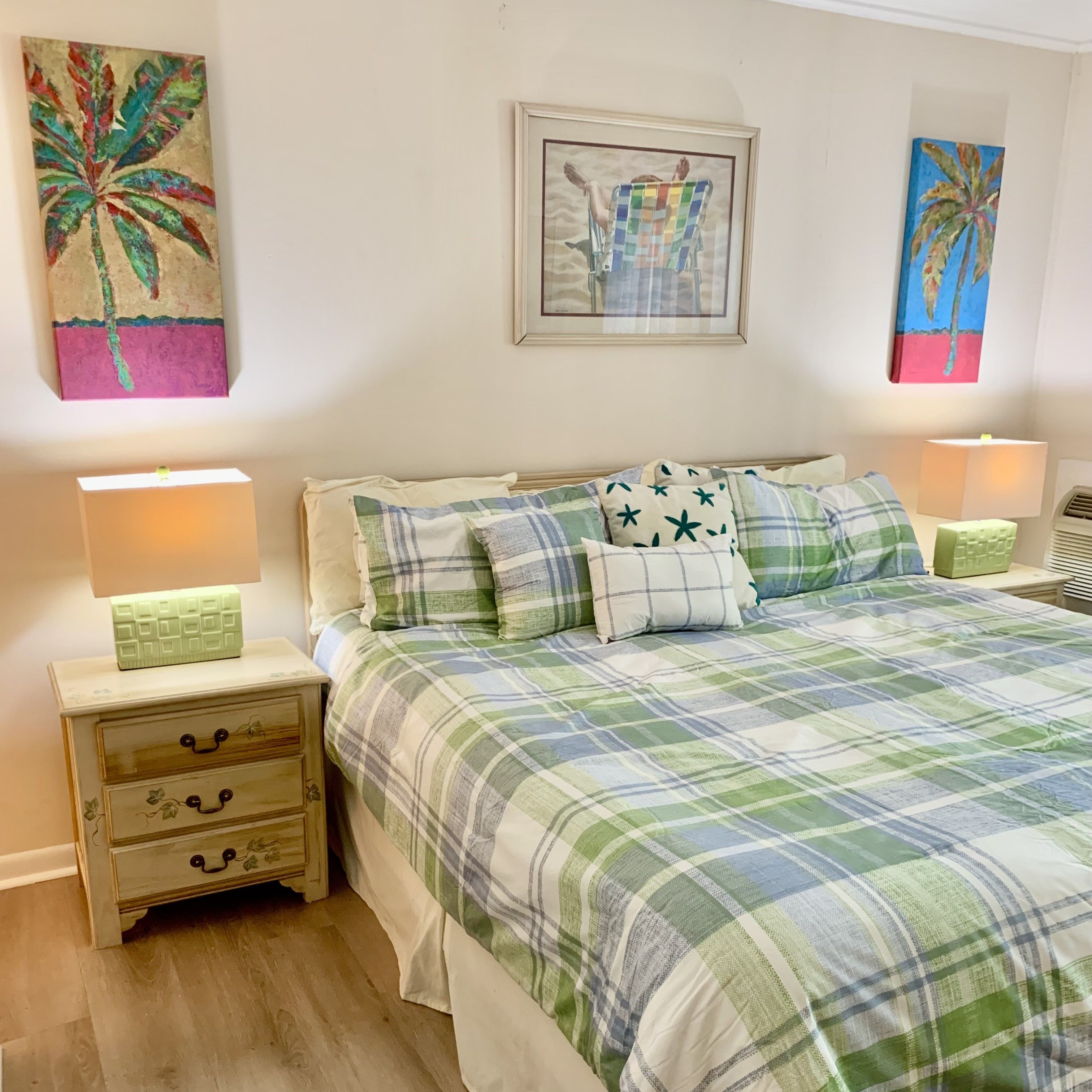 Een slaapkamer met een bed, twee nachtkastjes en een kunstwerk aan de muur.
