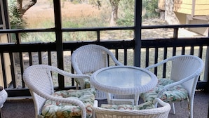 A covered outdoor seating area with wicker furniture and a glass-top table.