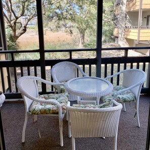 A covered outdoor seating area with wicker furniture and a glass-top table.