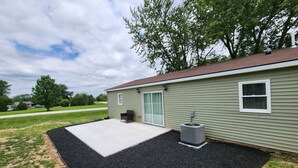 Einbungalow mit überdachter Terrasse, einer Schiebetür und einem kleinen Sitzbereich im Freien.