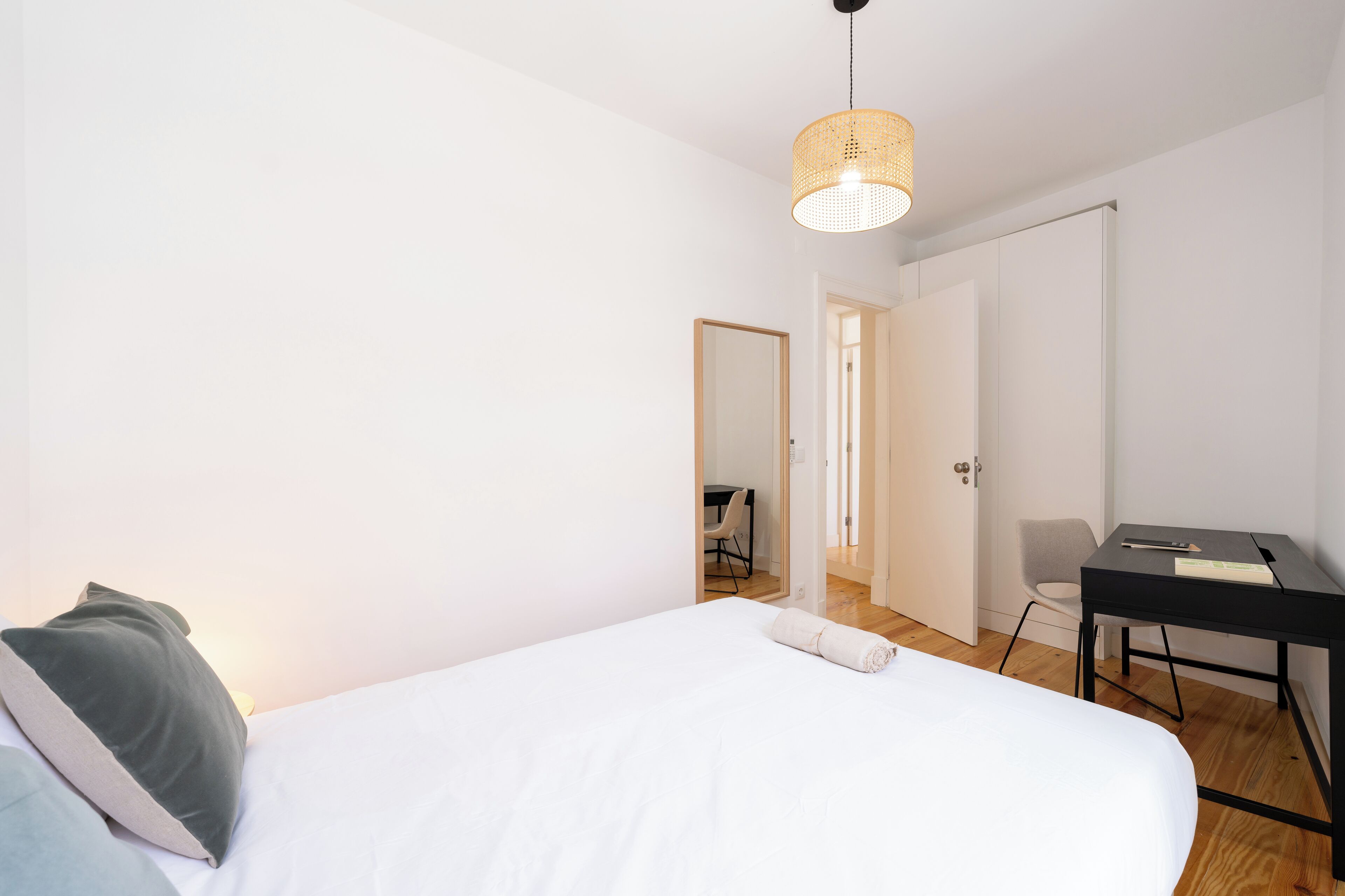 Un dormitorio minimalista con una cama individual, un escritorio y una silla.