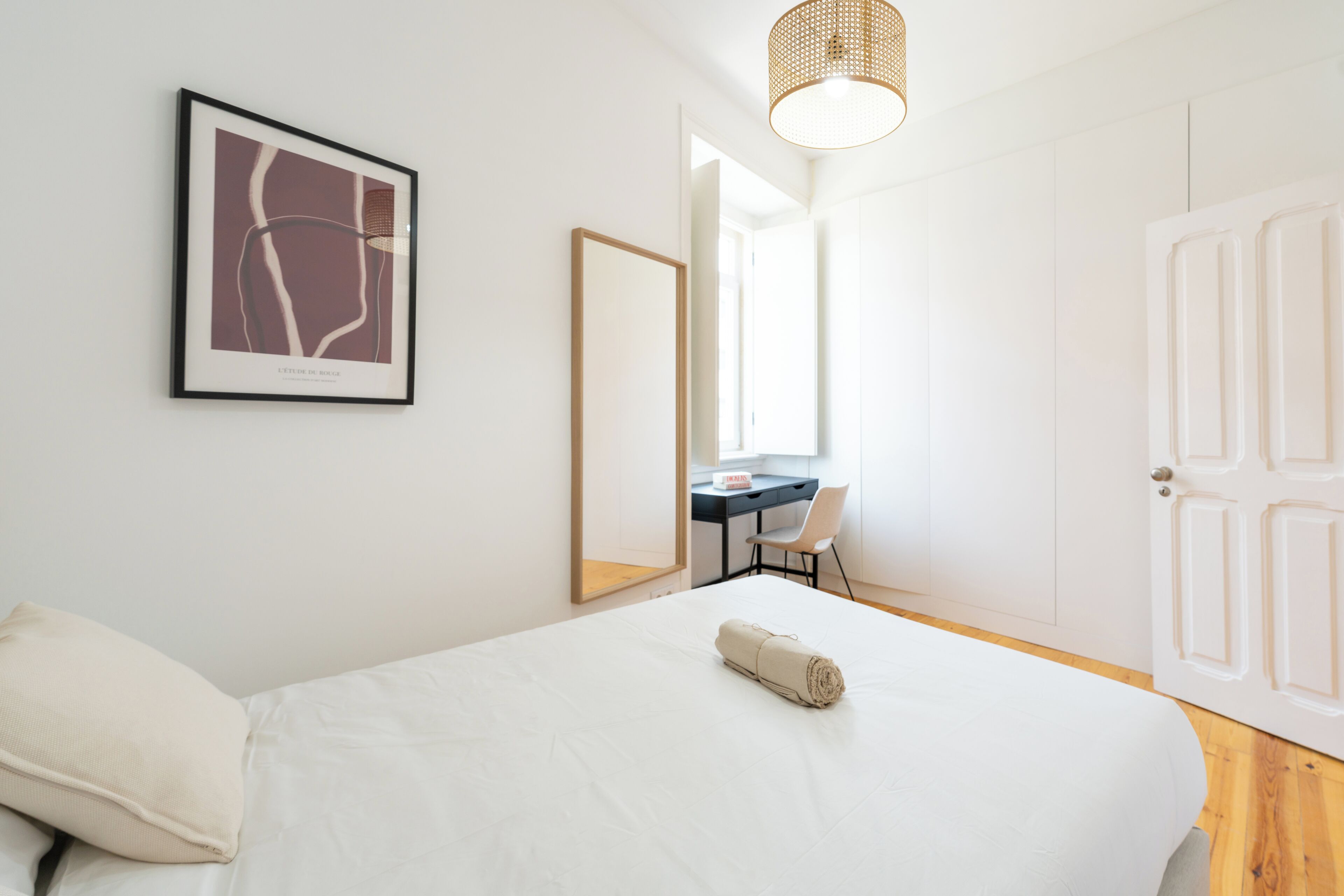 Een keurig opgemaakt slaapkamer met een bed, een bureau en een stoel.