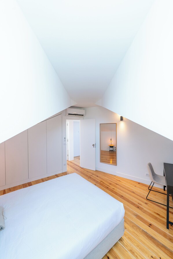 A modern bedroom with a sloped ceiling, a bed, a desk, and a mirror. - Sunny Lisbon Apartments by SoulPlaces (Lisbon)