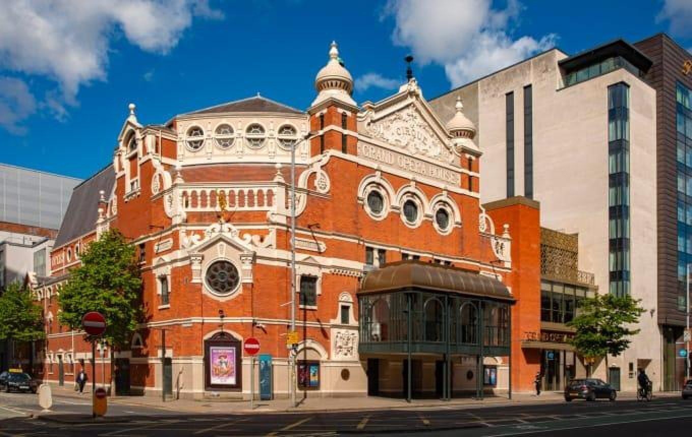 A historic building with ornate architecture, a prominent dome, and a modern glass extension.