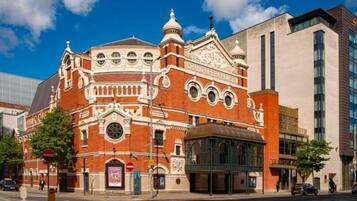A historic building with ornate architecture, a prominent dome, and a modern glass extension.