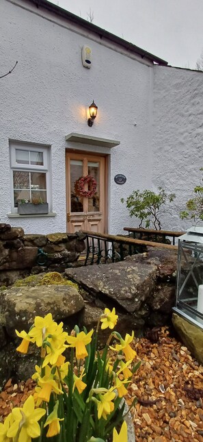 Quaint building with a wooden door, stone wall, and cozy outdoor seating area.