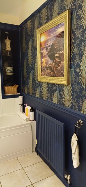 Bathroom features a bathtub, radiator, and decorative shelf.