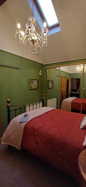 Relax in this serene space with a large bed, chandelier, and mirror.