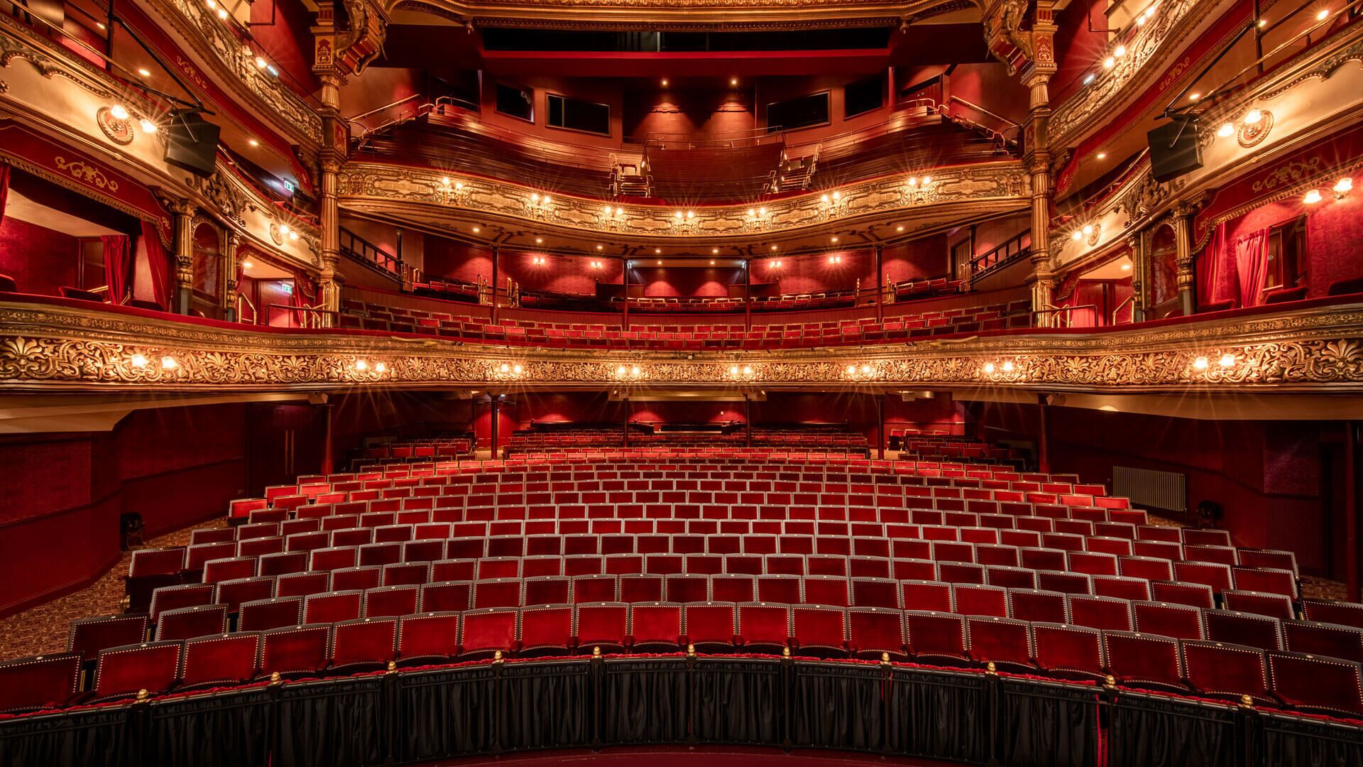 Un théâtre doté d’une scène centrale, de plusieurs balcons et de sièges rouges.