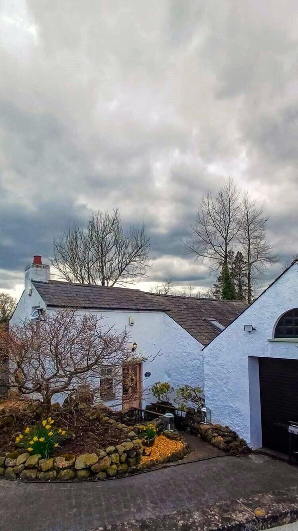 Set amidst a charming garden, this house features a steeply pitched roof and a cozy chimney.