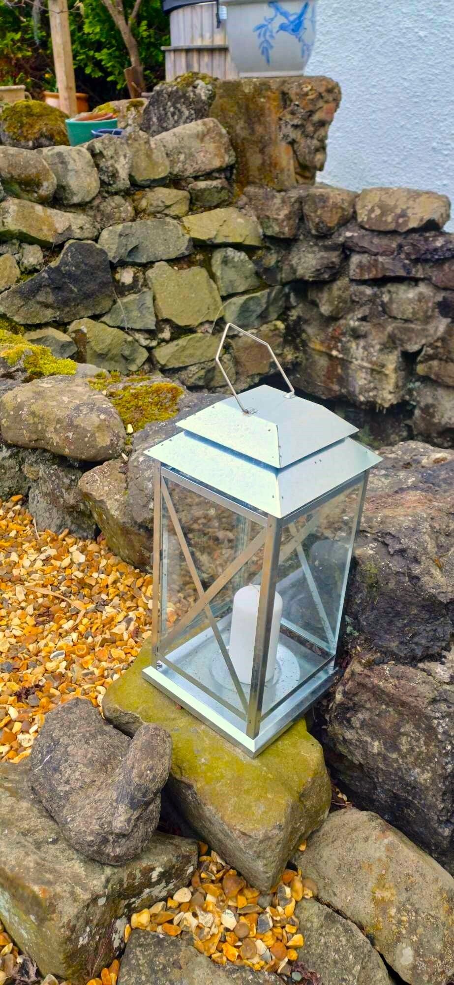 A lantern on a moss-covered rock near a stone wall.