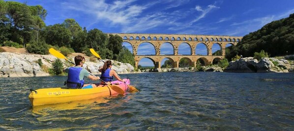 Two people kayaking on a river with a stone bridge in the background. - Apartment with a Private Courtyard - Between Uzès and Nîmes (Sainte-Anastasie)