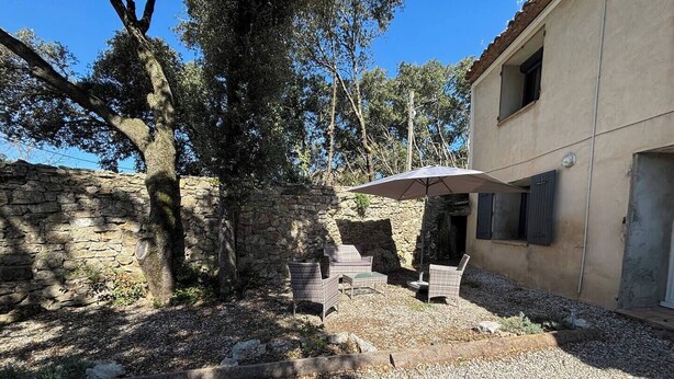 Un muro de piedra, asientos exteriores y un edificio con una ventana.