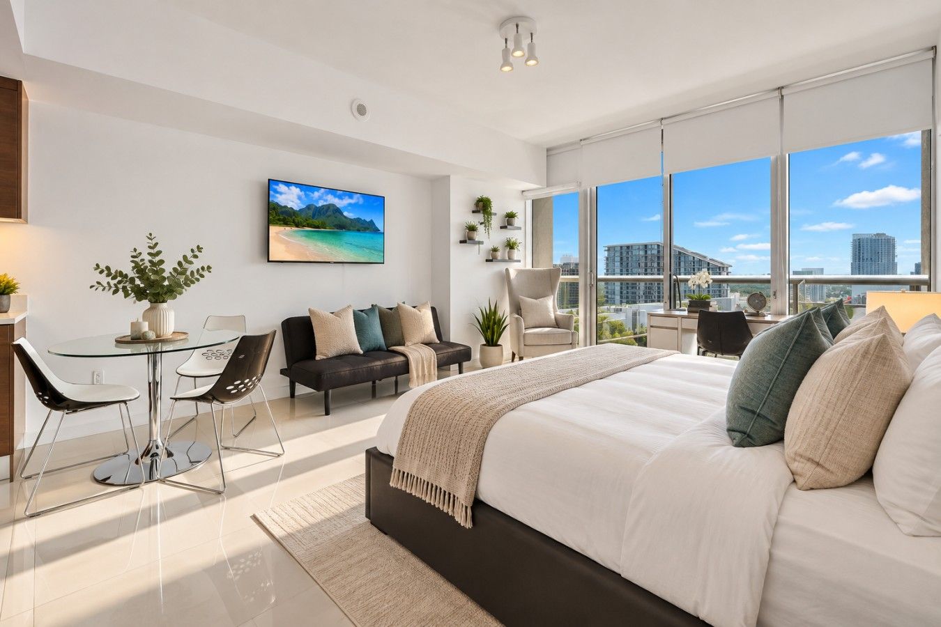 Une chambre moderne avec un grand lit, un canapé, une table à manger et des chaises. Une grande fenêtre offre une vue sur la ville.