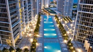 A high-rise hotel with multiple swimming pools and a well-lit outdoor area.