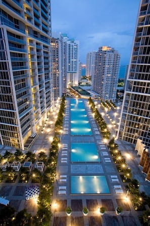 A high-rise hotel with multiple swimming pools and a well-lit outdoor area.