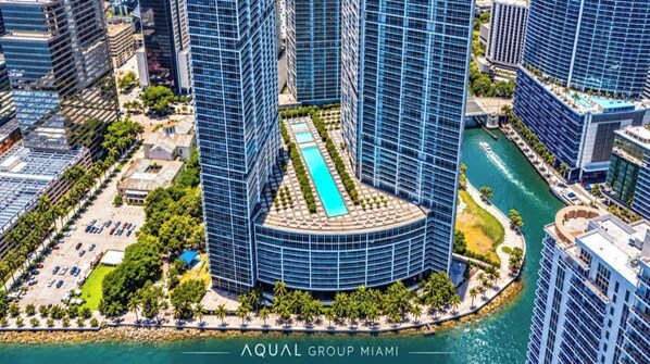 A high-rise building with a central courtyard, a swimming pool, and a waterfront view. - STUDIO APARTMENT DOWNTOWN | ICON-BRICKELL (Miami)