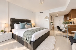 A modern bedroom with a large bed, bedside tables, a desk, and a chair.