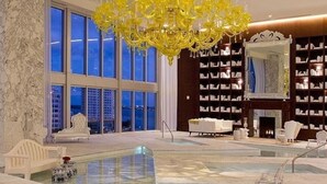 A spacious lobby with a large chandelier, a pool, and a library with bookshelves.