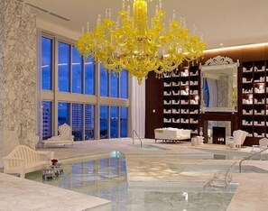 A spacious lobby with a large chandelier, a pool, and a library with bookshelves.