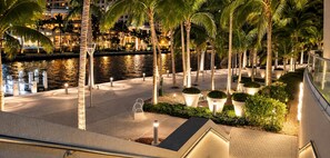 A nighttime view of a waterfront hotel with palm trees, a pool, and illuminated pathways. - STUDIO APARTMENT DOWNTOWN | ICON-BRICKELL (Miami)