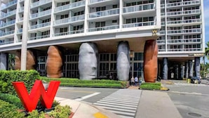 A modern hotel with a large 'W' logo, a pedestrian crossing, and a well-maintained landscaped area.