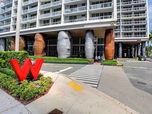 A modern hotel with a large 'W' logo, a pedestrian crossing, and a well-maintained landscaped area.