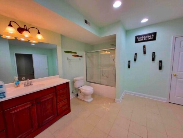 A bathroom with a red vanity, a toilet, a shower, and a sign indicating a 'Friendly Gather At Smith Mt. Lake'. - 3 Kayaks, 1 Canoe, Wifi, Community swimming pool, Community Tennis, Foosball, gas grill, ice maker. kurig (Moneta)