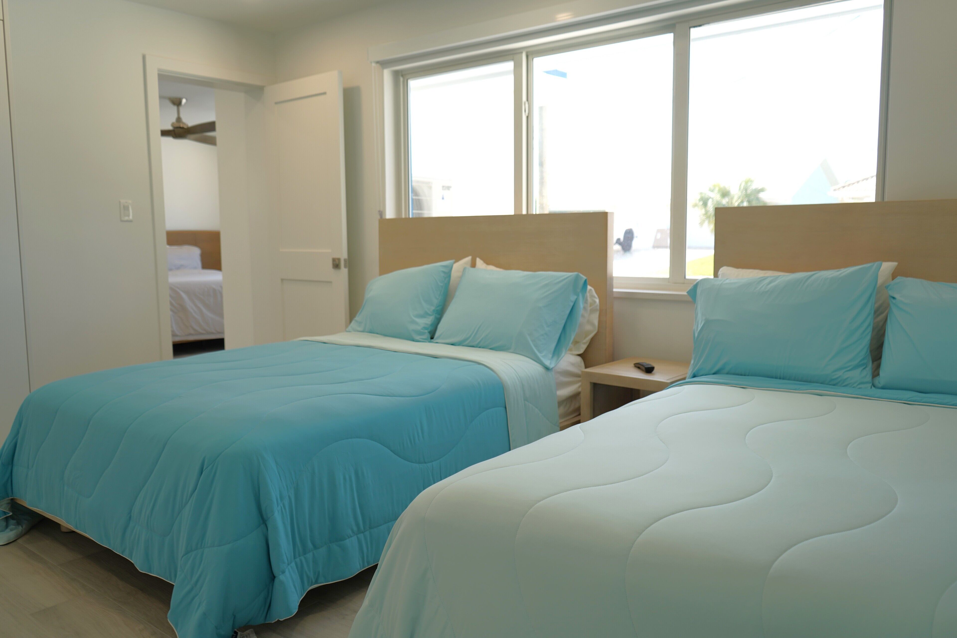 Une chambre d’hôtel avec deux lits, une fenêtre et une porte donnant sur une salle de bain.
