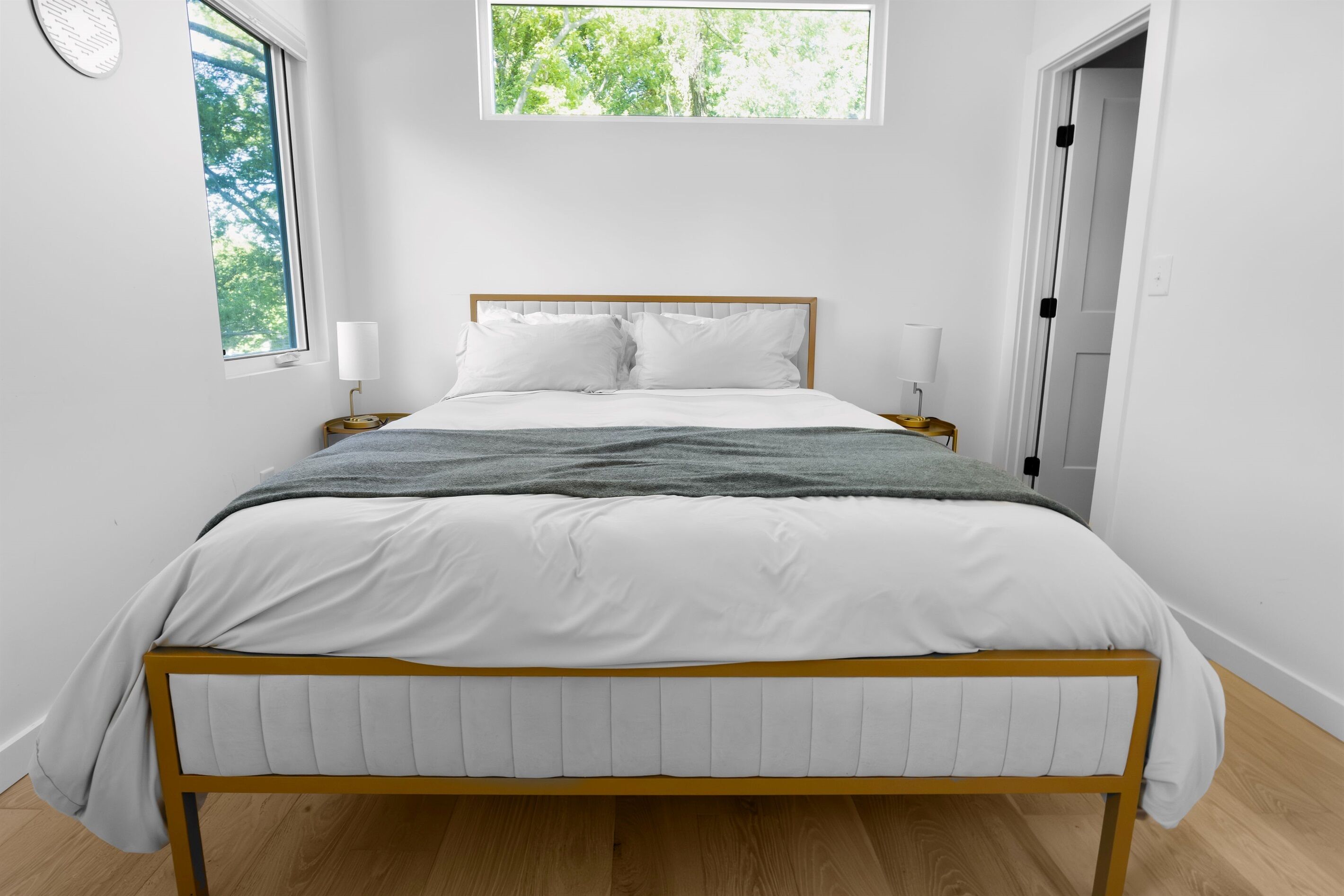 A bedroom with a bed, bedside lamps, a window, and a door.