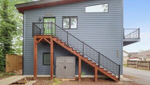 A two-story building with a green door, a staircase, and a garage door. - Modern suite | Mins from DT Raleigh | Workspace (Raleigh)