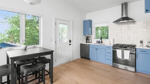 A modern kitchen with a dining area, large windows, and a stainless steel stove. - Modern suite | Mins from DT Raleigh | Workspace (Raleigh)