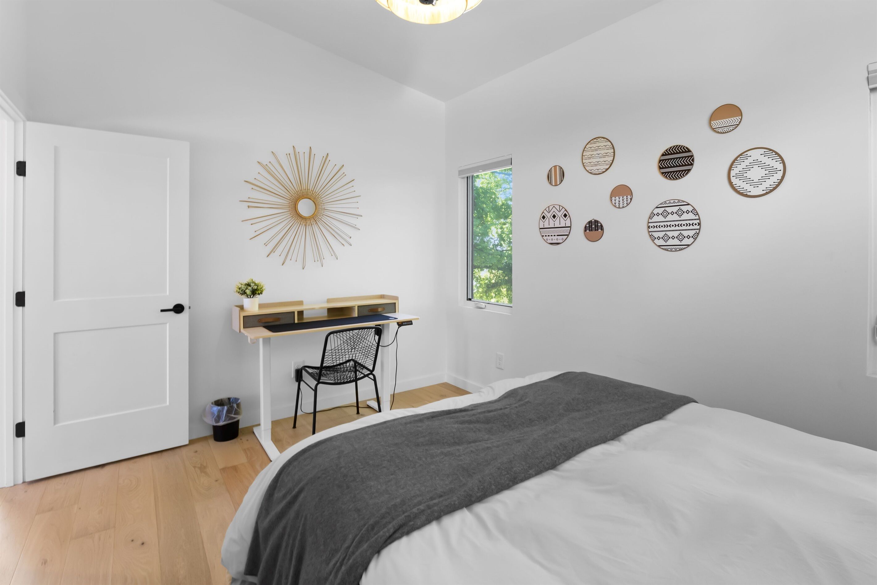 A bedroom with a bed, a desk, a chair, a window, and wall decorations.