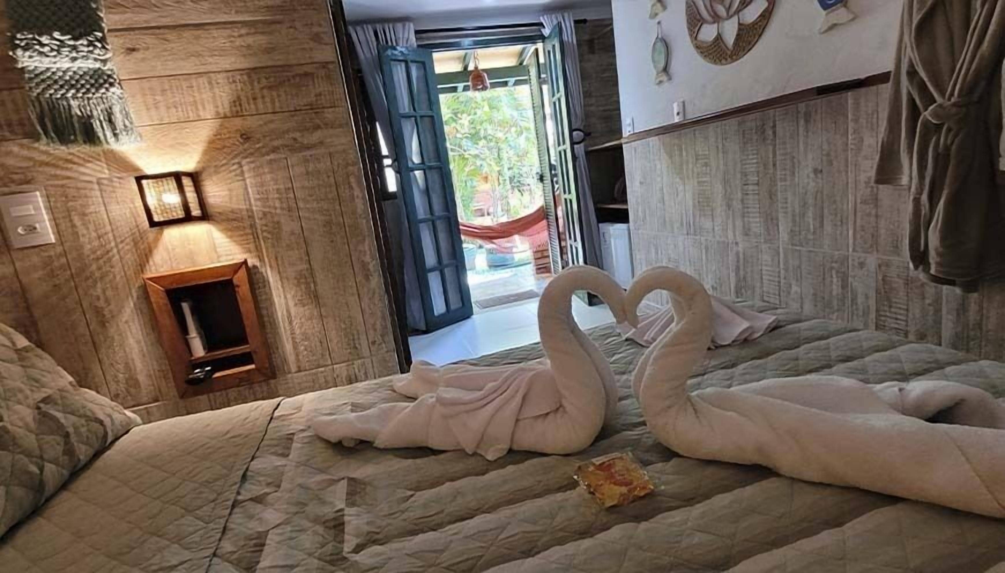 Habitación de hotel con cama, mesita de noche, lámpara de pared y vistas al exterior.