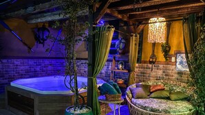 Een gezellig buitenzitgedeelte met een jacuzzi, rieten meubels en een decoratieve hanglamp.