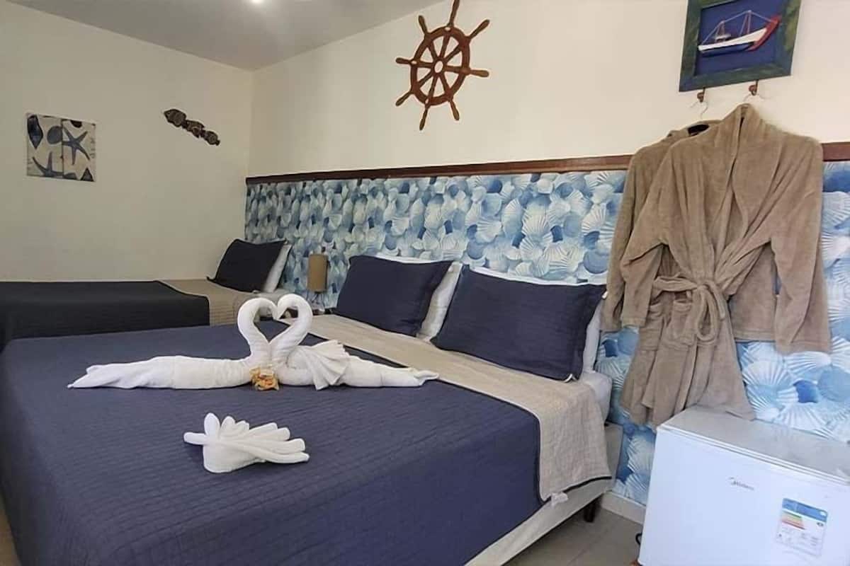 Une chambre d’hôtel avec deux lits, une décoration représentant un gouvernail de bateau et un tableau encadré au mur.