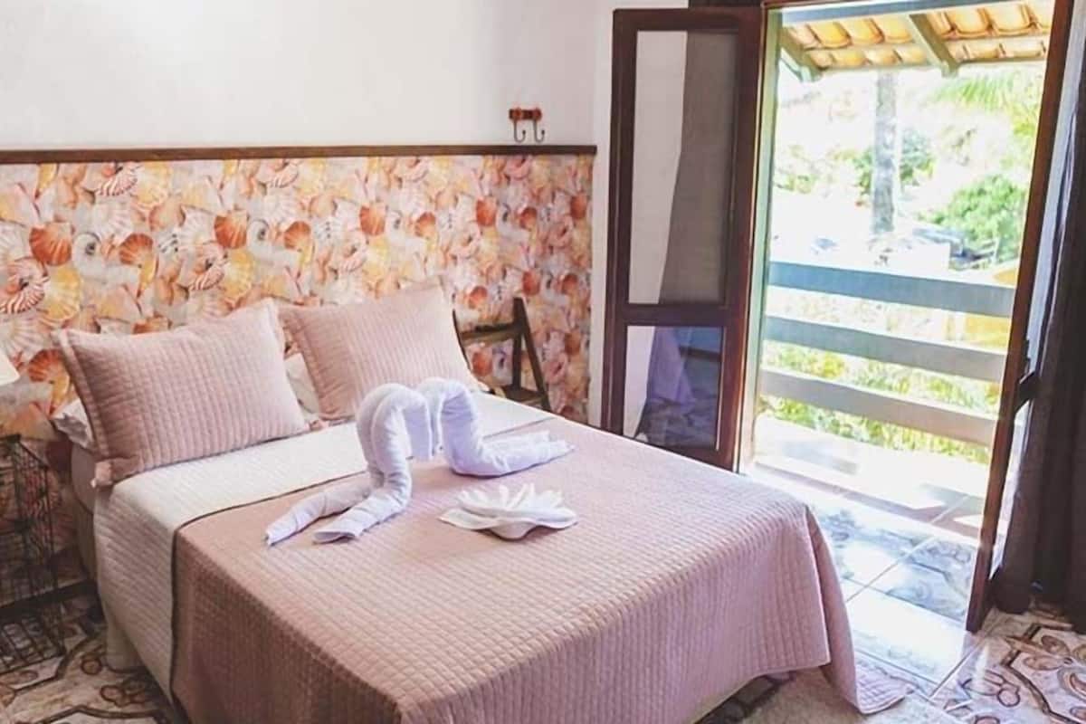 Une chambre d’hôtel avec un lit, des oreillers, une lampe et une vue sur l’extérieur.