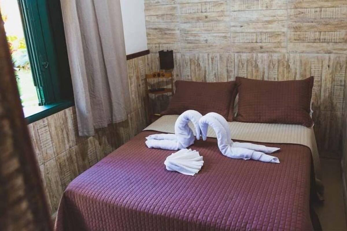 Une chambre d’hôtel avec un lit, une fenêtre avec des rideaux et un mur en bois.