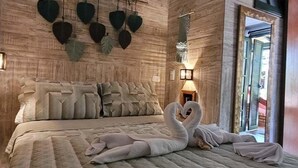 Een slaapkamer met een groot bed, decoratieve hartvormige muurdecoratie en een zwaan-vormige kussenopstelling.