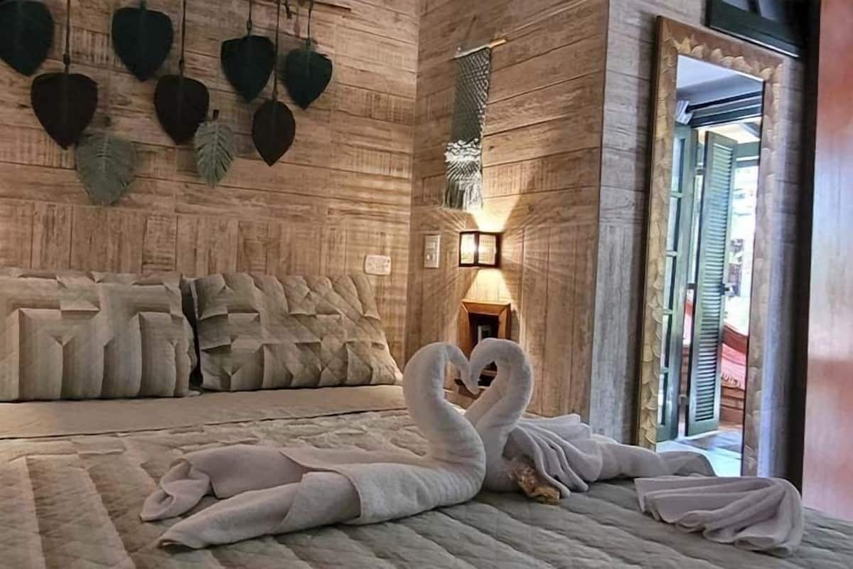 Une chambre avec un grand lit, des décorations murales en forme de cœur et un arrangement d’oreillers en forme de cygne.