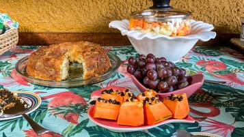 Una mesa con una bandeja de fruta, un pastel y un bol de uvas.
