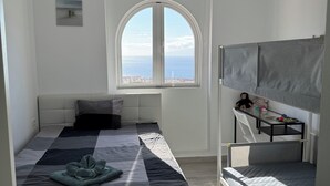 Een moderne slaapkamer met een groot bed, een stapelbed, een raam met uitzicht en een bijzondere plafondlamp.