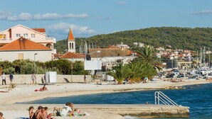 A beach with people sunbathing, a pier, and a church with a bell tower.